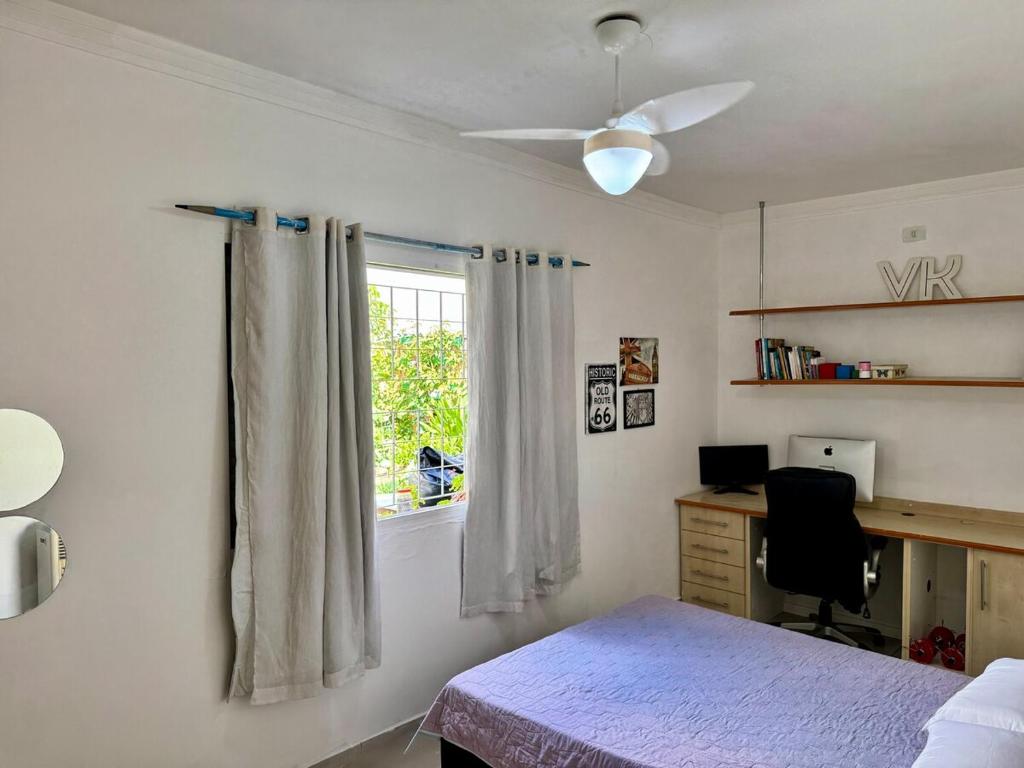 a bedroom with a bed and a desk and a window at Casa com Carregador para Carro e Quintal Pet, WiFi 500 in Jundiaí