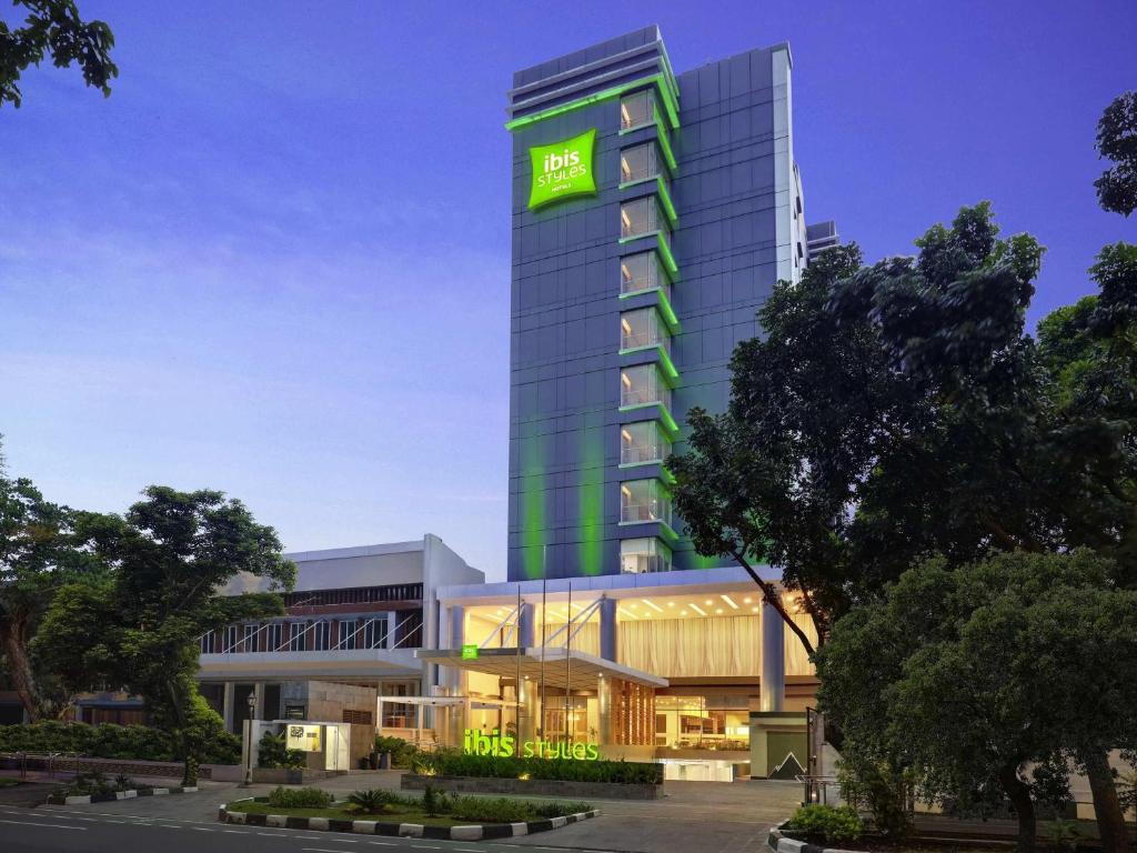 a tall building with a green sign on it at ibis Styles Bogor Pajajaran in Bogor