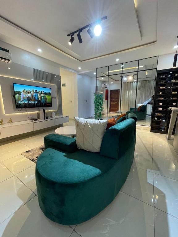 a living room with a green couch and a tv at EasyStay Apartments in Ogere
