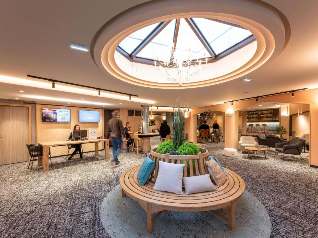 a large lobby with a couch and a chandelier at Novotel Macon Nord - Porte de Bourgogne in Mâcon