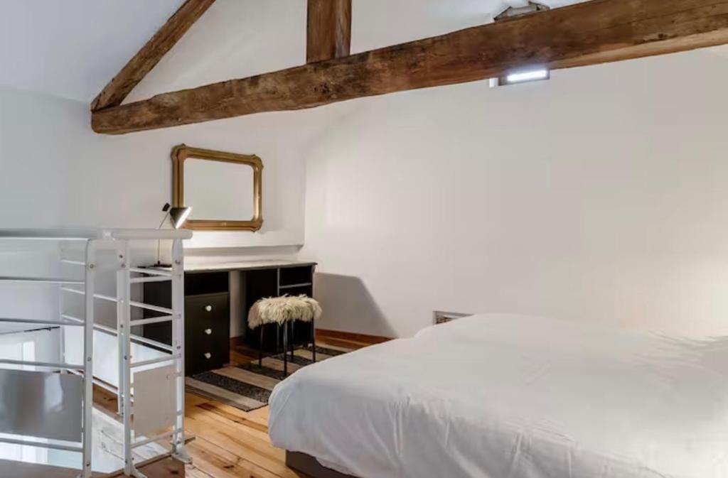 Un dormitorio con una cama blanca y un espejo. en Gîte avec piscine - La Chapelle, en Graulhet