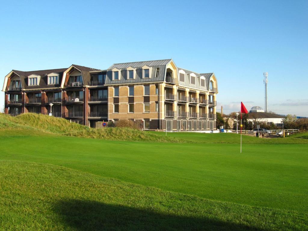 een groot gebouw bovenop een weelderig groen veld bij Residence Ruimzicht - Baddomburg in Domburg