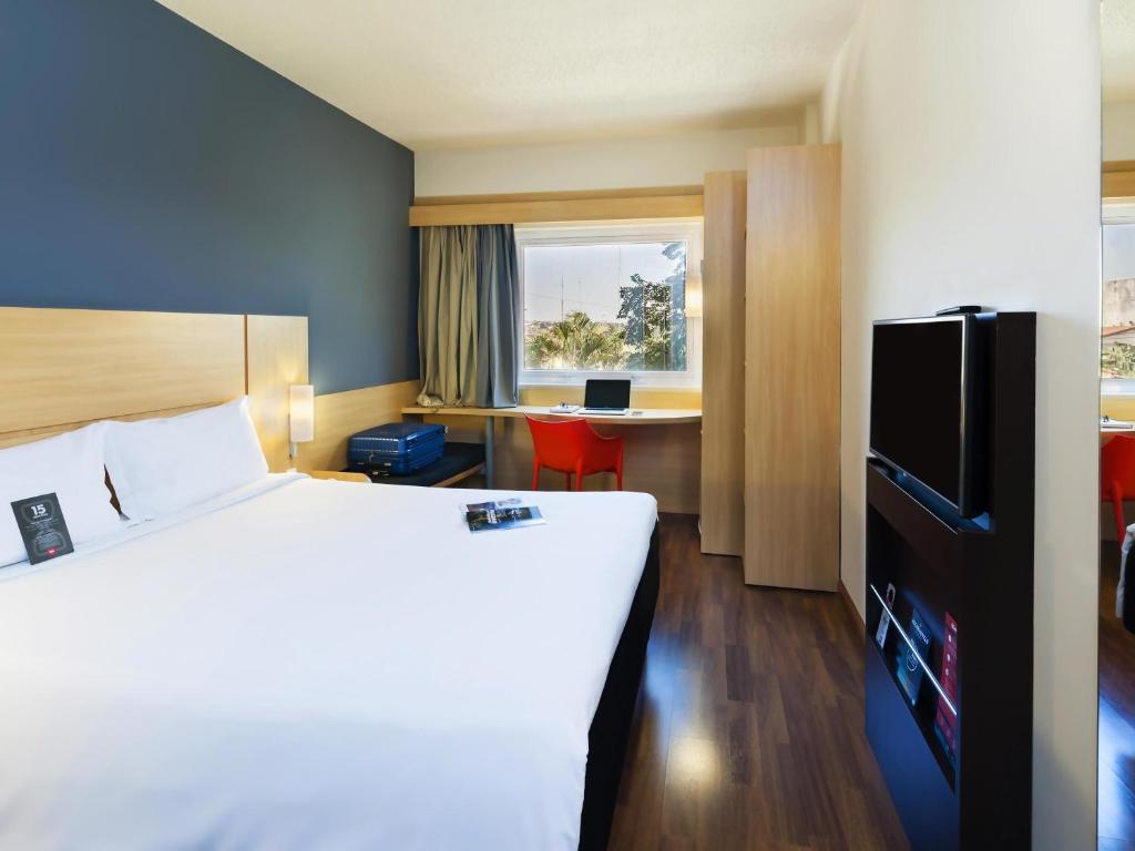 Una habitación de hotel con una cama grande y un escritorio. en ibis Paulinia, en Paulínia