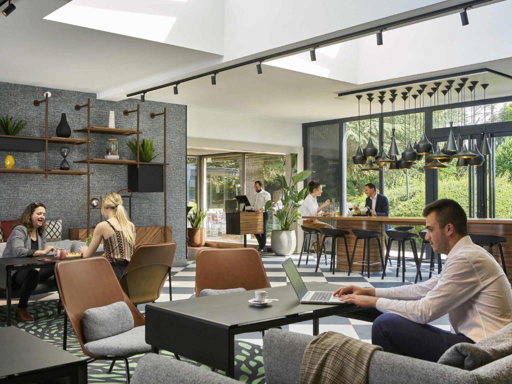 a group of people sitting at tables with a laptop at Novotel Massy Palaiseau in Palaiseau