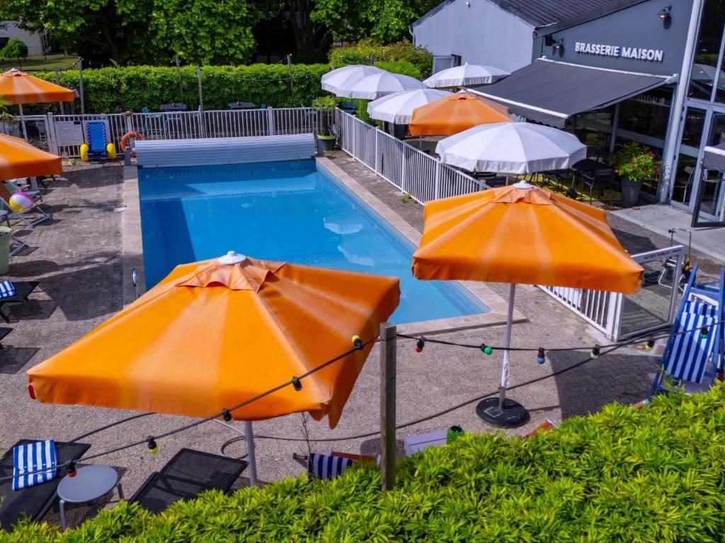a group of umbrellas and a pool with chairs at Mercure Reims Parc Des Expositions in Reims