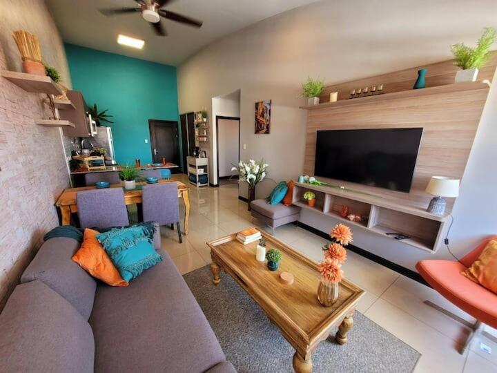a living room with a couch and a table and a tv at Near Airport - Lush Gardens, Pool, King Bed, Security in Santa Ana