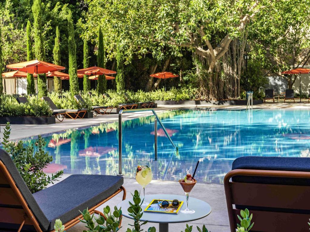 ein Swimmingpool mit einem Tisch und einem Getränk daneben in der Unterkunft Mercure Benidorm in Benidorm