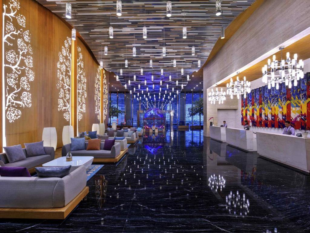 a lobby with couches and chandeliers in a building at Grand Mercure Jakarta Kemayoran in Jakarta