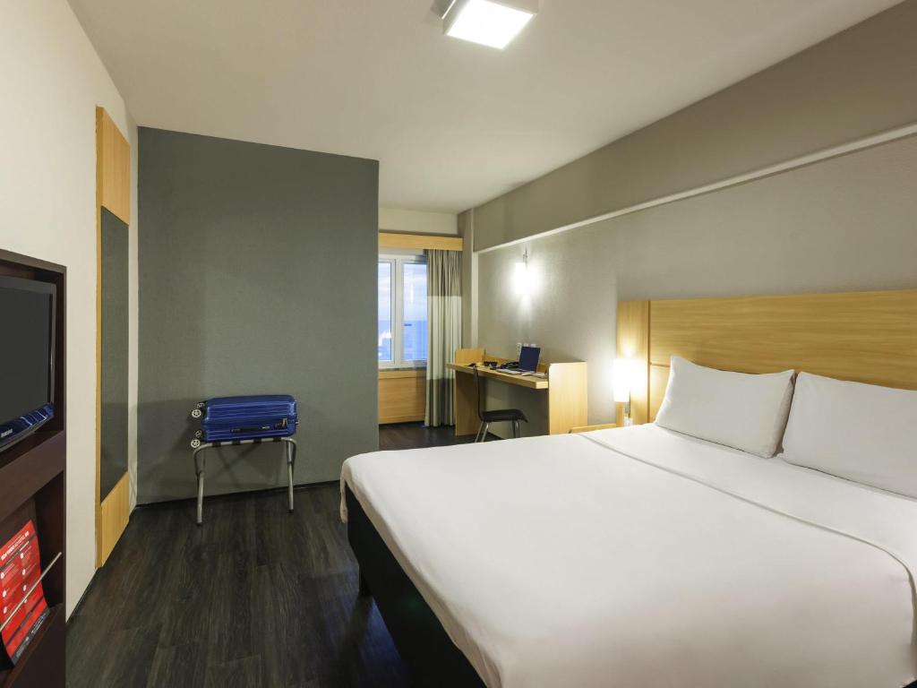 a hotel room with a large bed and a desk at ibis Fortaleza Praia de Iracema in Fortaleza