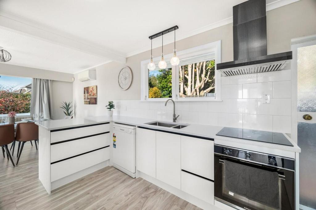 a white kitchen with a sink and a stove at 5 Bedrooms Lake View Cosy Place in Rotorua