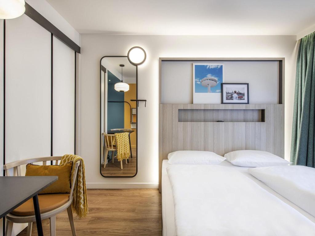a bedroom with a bed and a table and a chair at Aparthotel Adagio access Hamburg in Hamburg
