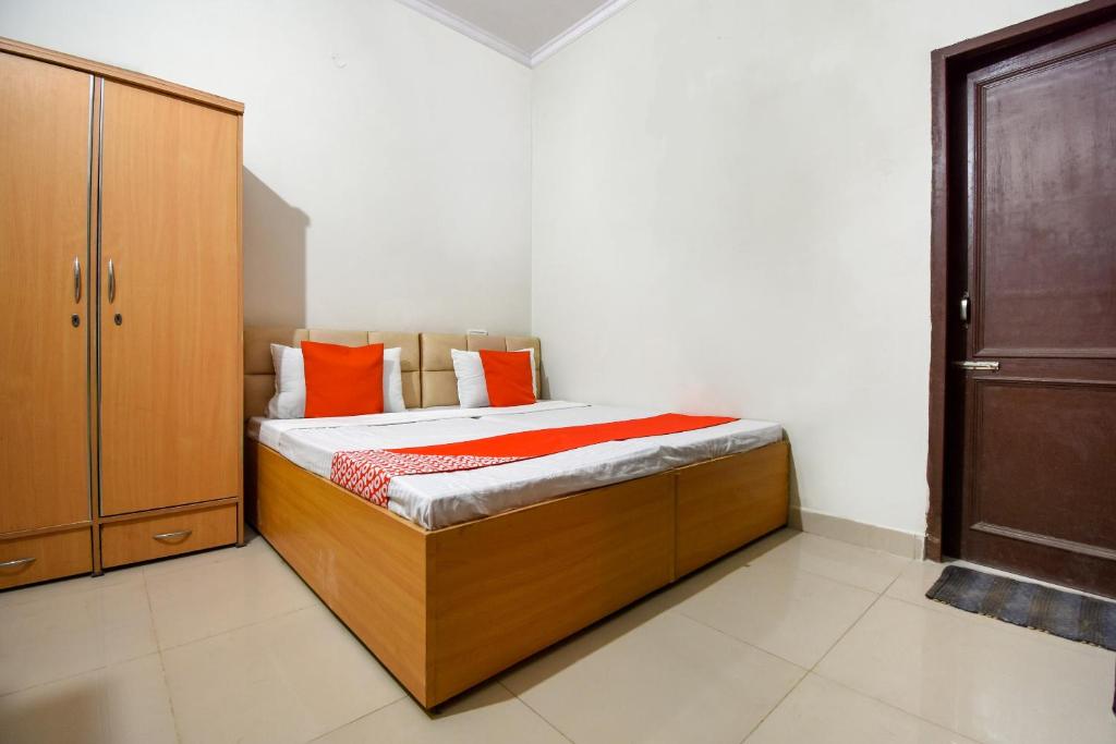a bedroom with a bed with orange pillows at Hotel O Sabtera Homes in Kharar