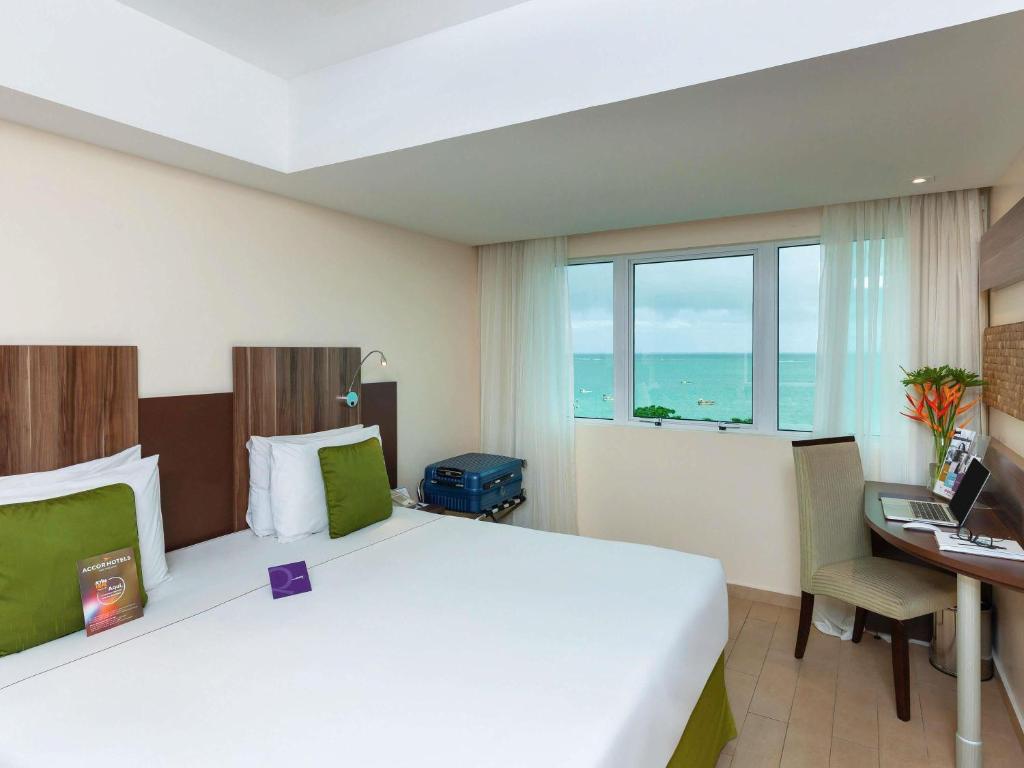 pokój hotelowy z łóżkiem, biurkiem i oknem w obiekcie Mercure Maceio Pajuçara w mieście Maceió