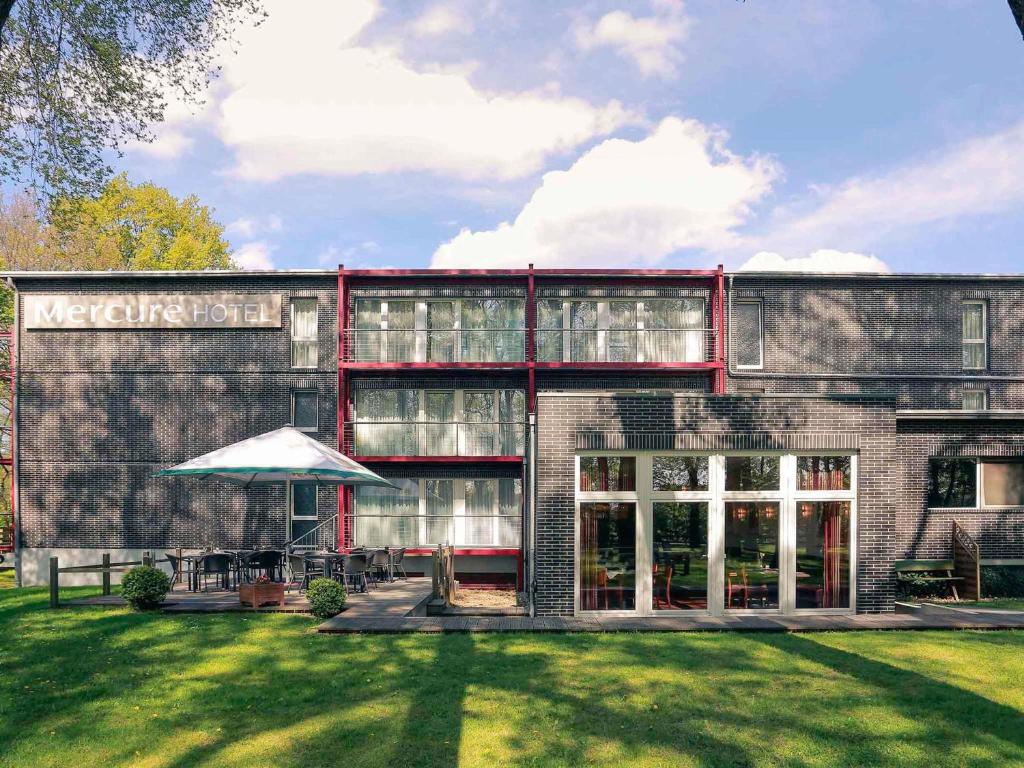 a building with a lawn in front of it at Mercure Hotel am Entenfang Hannover in Hannover