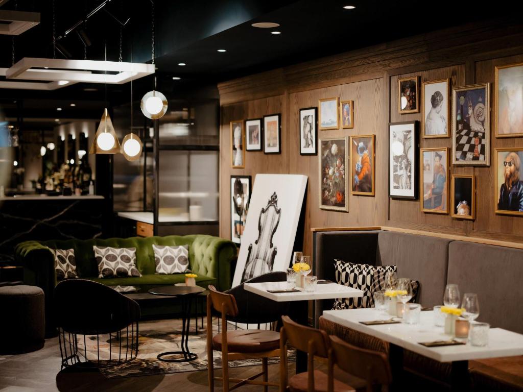 un restaurante con 2 mesas y un sofá verde en Novotel Den Haag City Centre, en La Haya