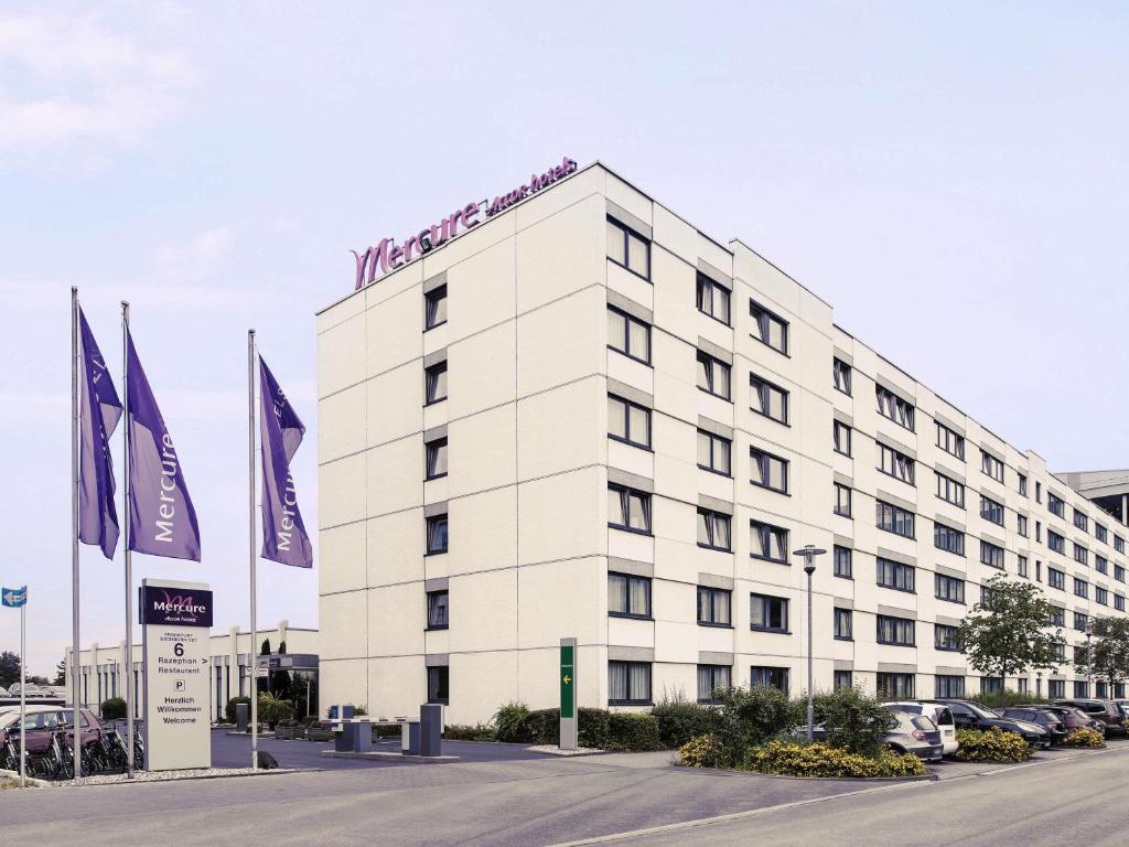 a white building with flags in front of it at Mercure Hotel Frankfurt Eschborn Ost in Eschborn