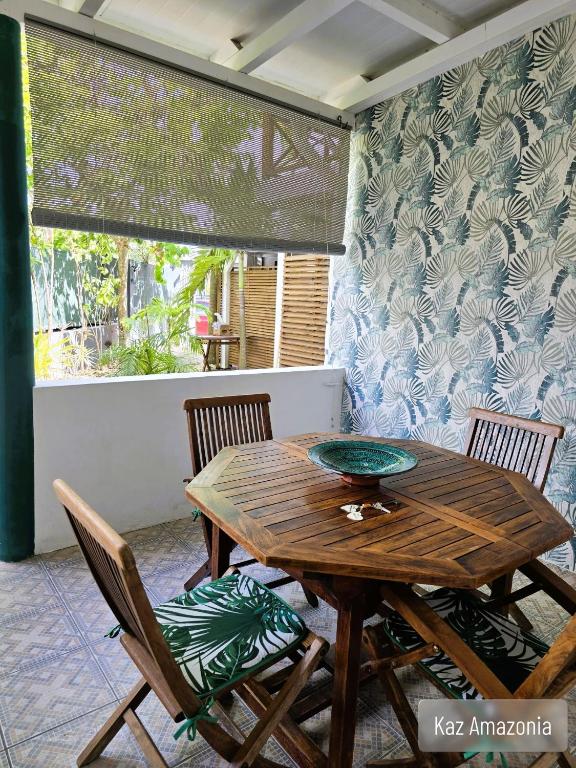 a wooden table and chairs in a room with a window at Gîtes Kaz Tchò in Sainte-Anne