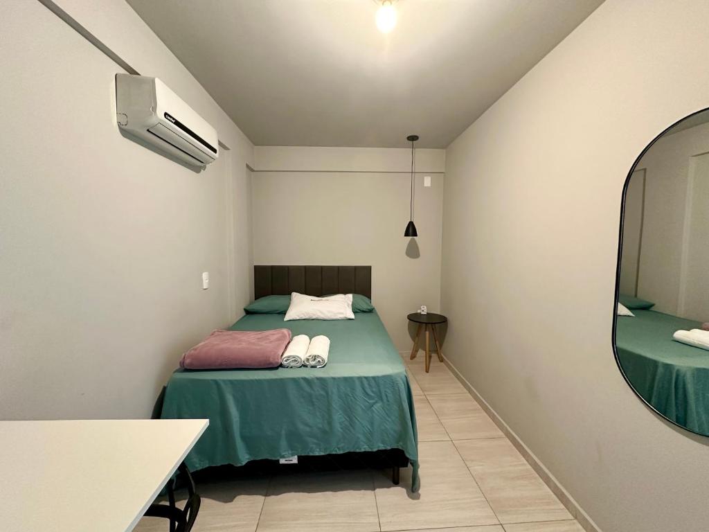 Un dormitorio pequeño con una cama y un espejo. en Pousada da Laís, en Blumenau