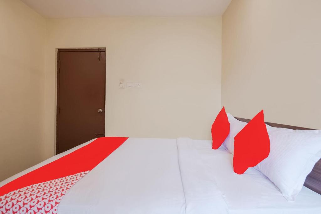 a bedroom with a bed with red and white pillows at Hotel O Anu Grand in Visakhapatnam