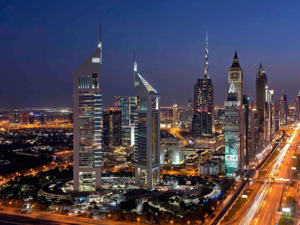 un perfil urbano por la noche con una torre de reloj en Swissôtel Al Murooj Dubai, en Dubái
