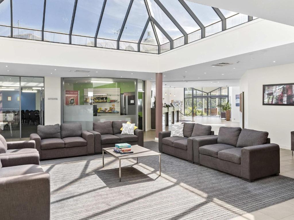 sala de estar con sofás y techo de cristal en ibis Styles Canberra Eagle Hawk, en Canberra