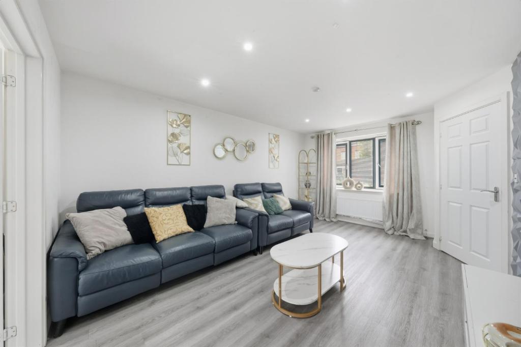 a living room with a blue couch and a table at Lara's 4 Bedroom House near Coventry in Coventry
