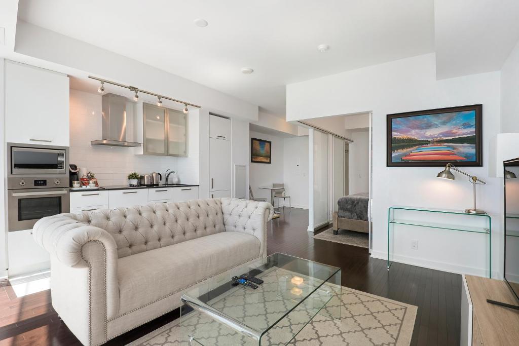 a living room with a couch and a glass table at Luxury 1BR Suite - Lake & City View on 39th Floor in Toronto