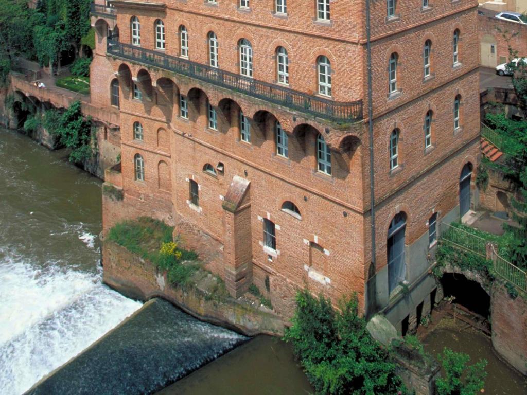 an aerial view of a large brick building next to a river at Mercure Albi Rives du Tarn in Albi