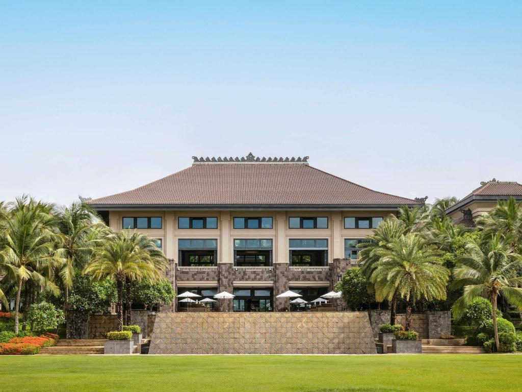 a building with palm trees in front of it at Raffles Hainan Clear Water Bay in Sanya