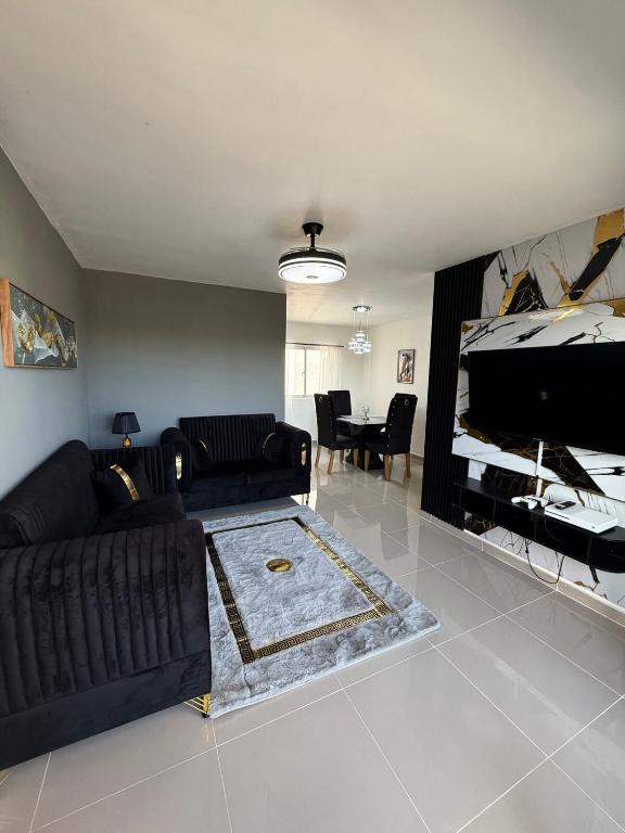 a living room with a black couch and a piano at Alma Ivet III 5min From The Airport & Boca Chica Beach in Monte Adentro