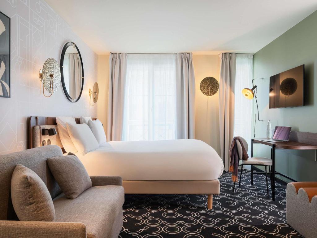 a hotel room with a large bed and a couch at Mercure Paris Opera Grands Boulevards in Paris