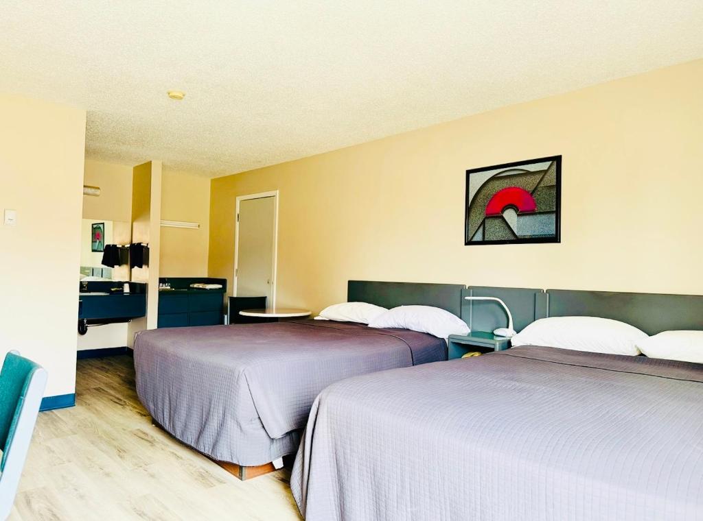 a hotel room with two beds and a bathroom at Plains Motor Inn in Stettler