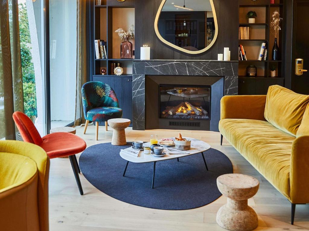 a living room with a couch and a fireplace at Mercure Beaune Centre in Beaune