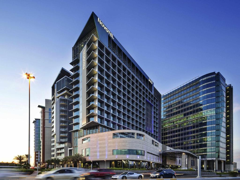 a large building with cars driving in front of it at Novotel Abu Dhabi Al Bustan in Abu Dhabi
