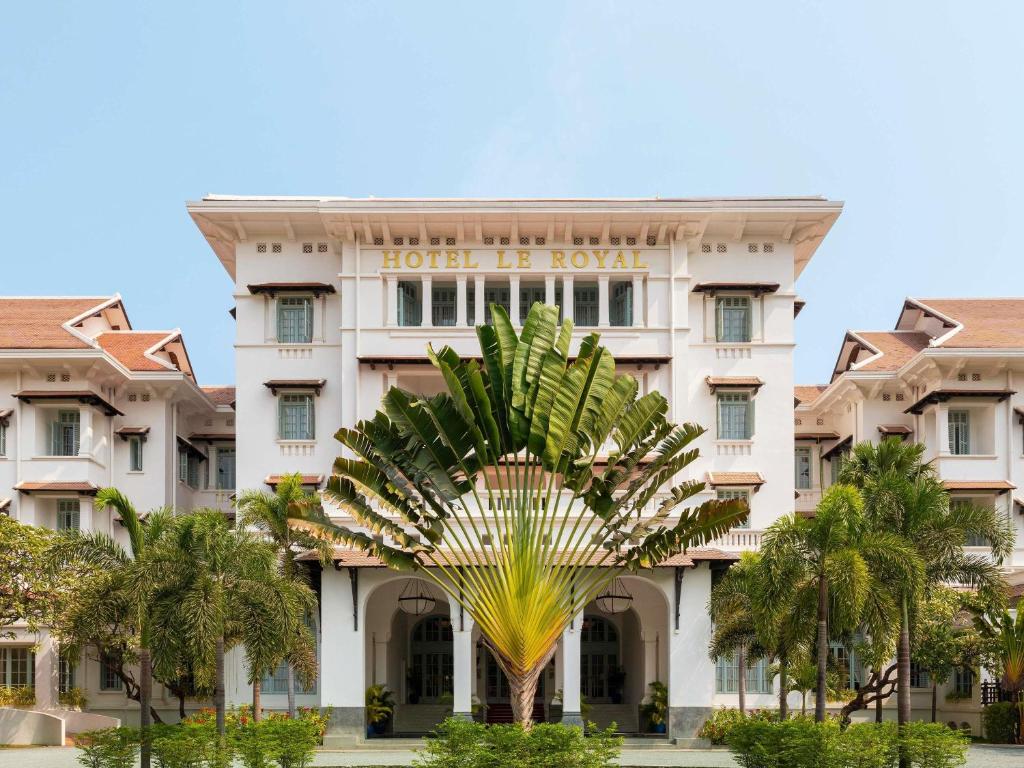a hotel with a palm tree in front of it at Raffles Hotel Le Royal in Phnom Penh