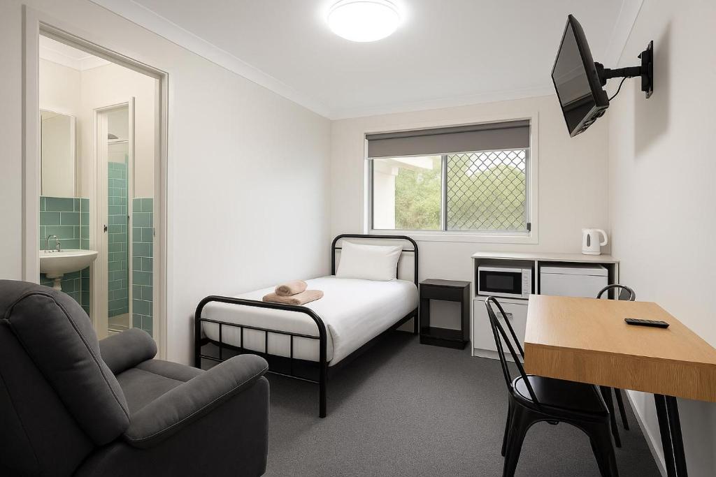 a bedroom with a bed and a desk and a chair at Brook Village in Muswellbrook