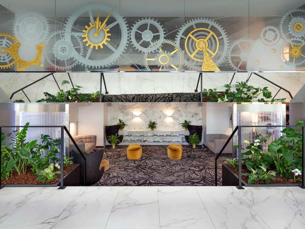a lobby with plants and a wall with clocks at Mercure Biel in Biel