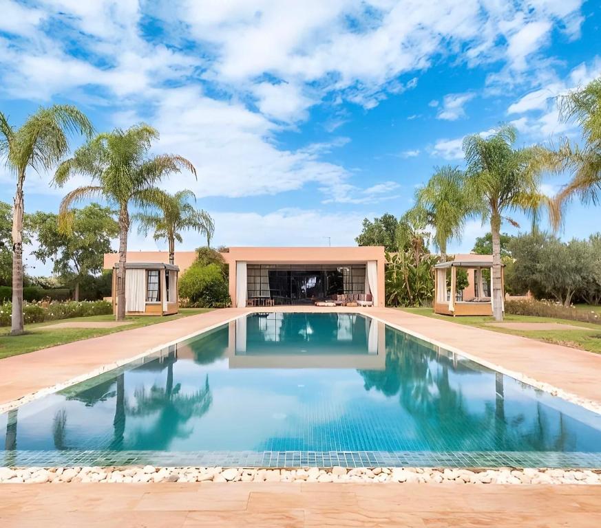 a swimming pool in a house with palm trees at Villa Serenity Marrakech in Châba