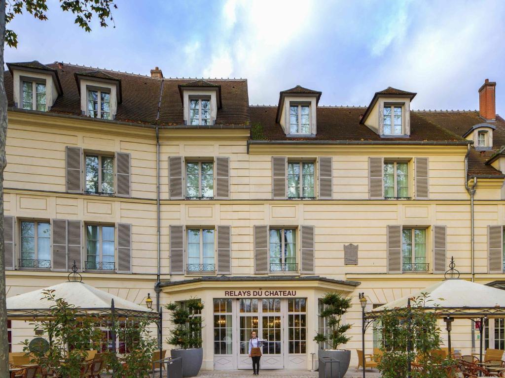 un grande edificio giallo con una donna in piedi di fronte di Mercure Rambouillet Relays Du Château a Rambouillet