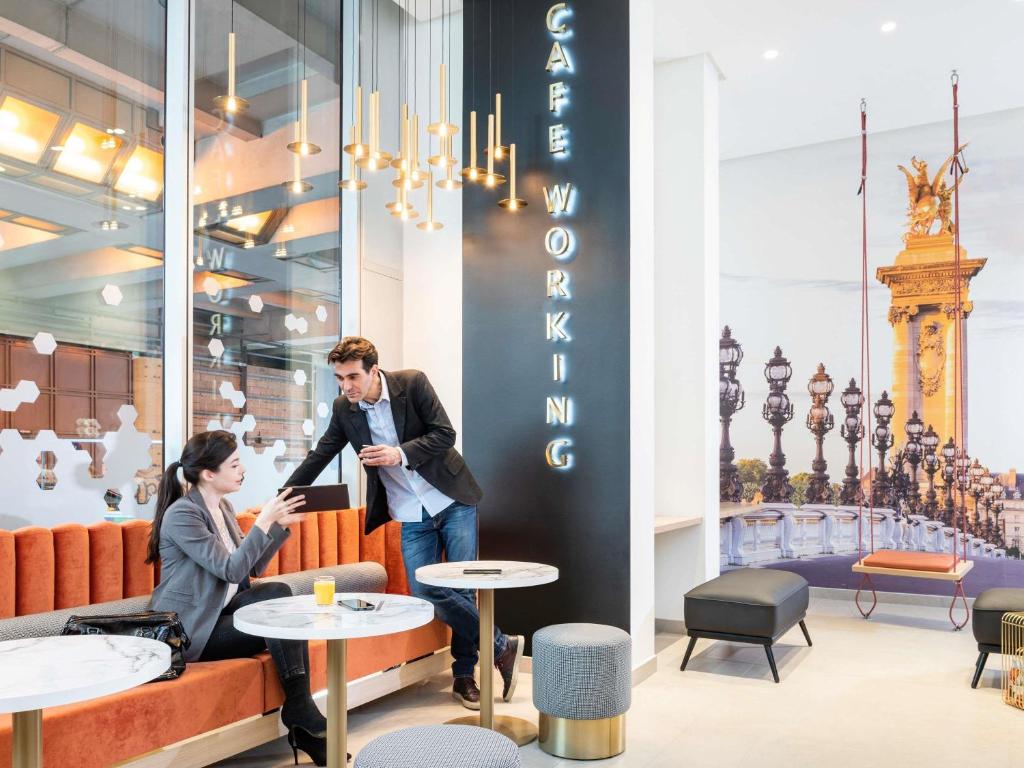 a man and a woman sitting at tables in a restaurant at Aparthotel Adagio Paris Centre Tour Eiffel in Paris