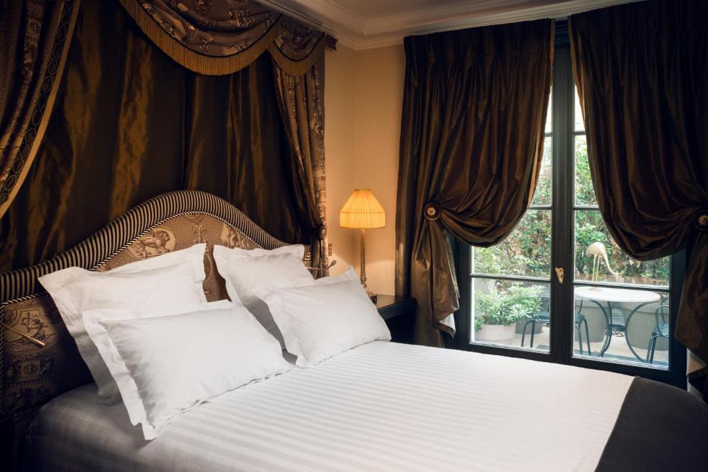 a bedroom with a bed with white pillows and a window at Maison Athénée in Paris