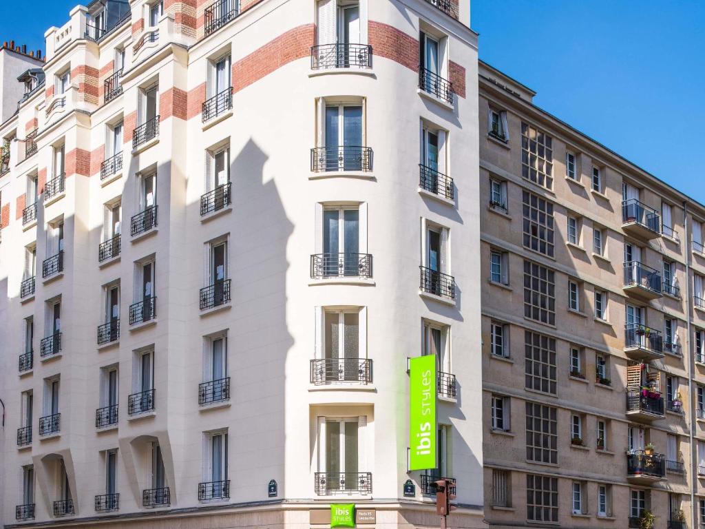 un edificio blanco con una señal verde delante de él en ibis Styles Paris 15 Lecourbe, en París