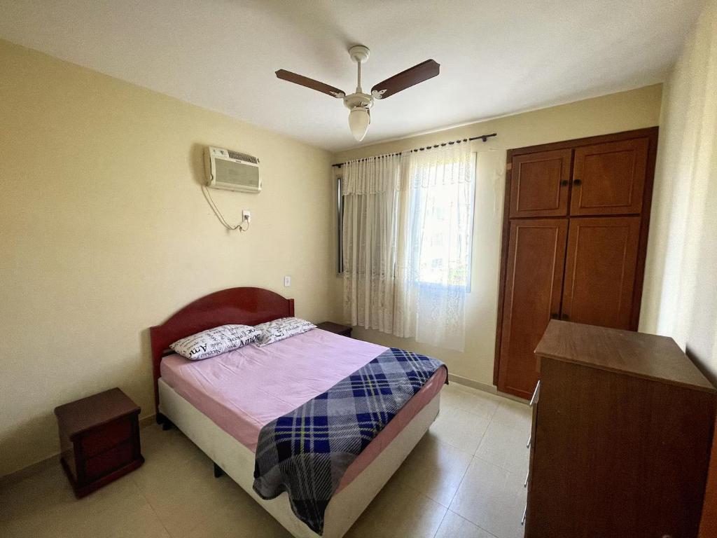 ein Schlafzimmer mit einem Bett und einem Deckenventilator in der Unterkunft Apartamento 2 Quadras da Praia da Enseada in Guarujá