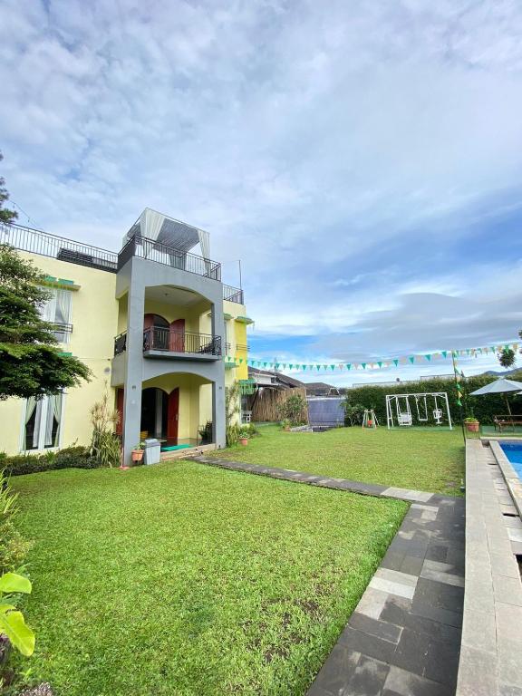a house with a green yard with a pool at Villa 99 Nabila Kayna Puncak in Paragajen