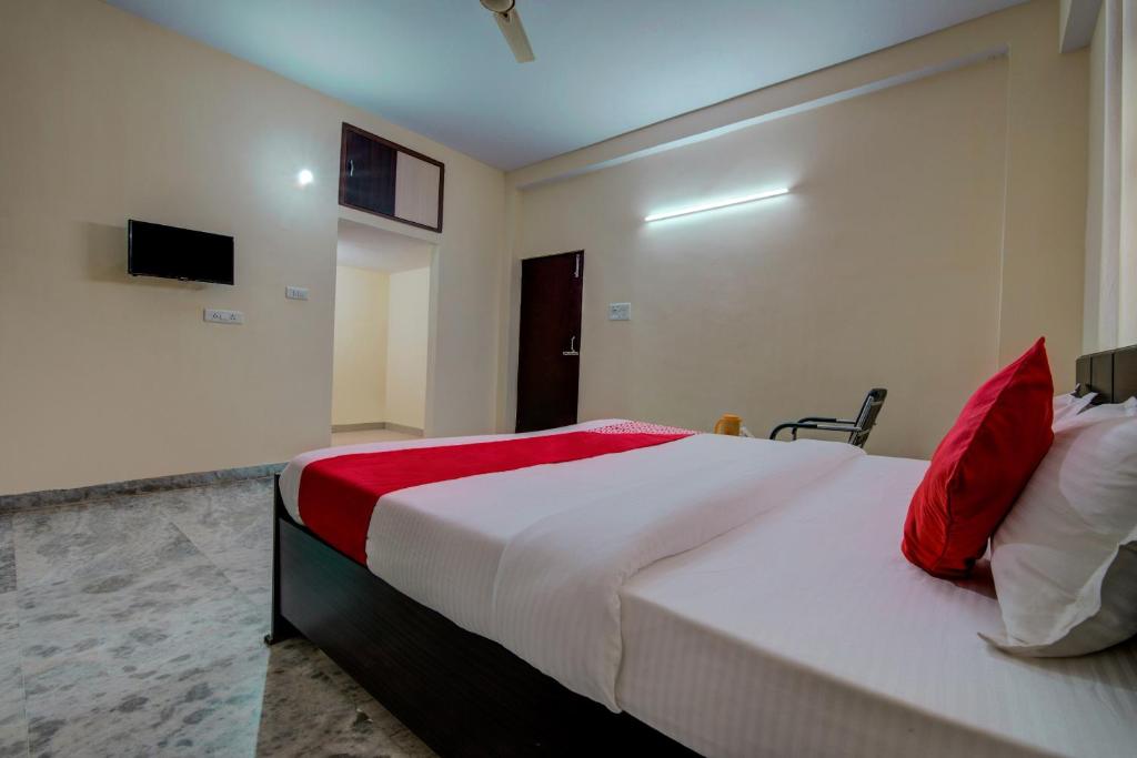 a bedroom with a large white bed with red pillows at Super Hotel O Rajbanshi Nagar in Patna
