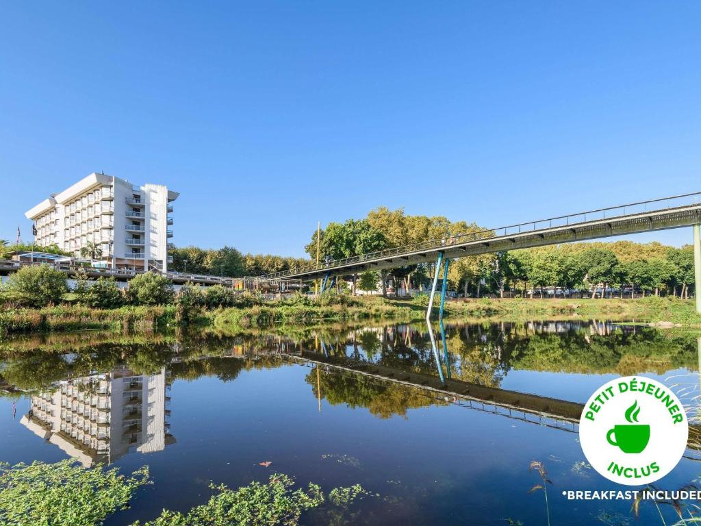 a bridge over a river with a building in the background at ibis styles Dax Centre in Dax