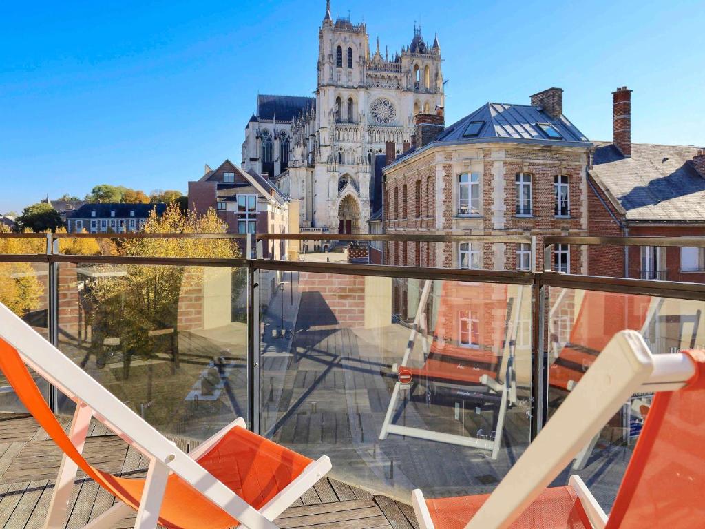 two chairs on a balcony with a view of a building at Mercure Amiens Cathédrale in Amiens