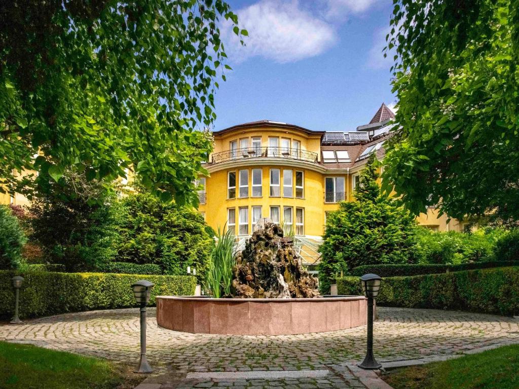 a yellow building with a fountain in front of it at Maison Sofia - MGallery in Sofia