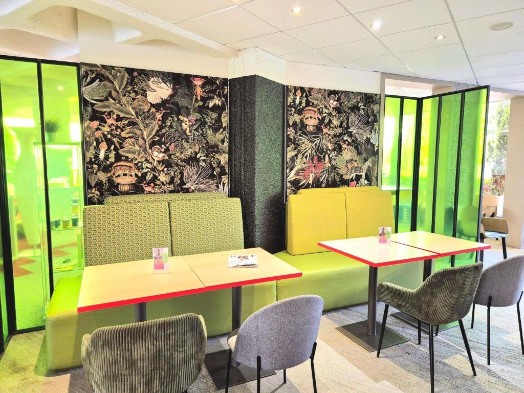 uma sala de jantar com duas mesas e cadeiras em ibis Styles Tours Sud em Chambray-lès-Tours