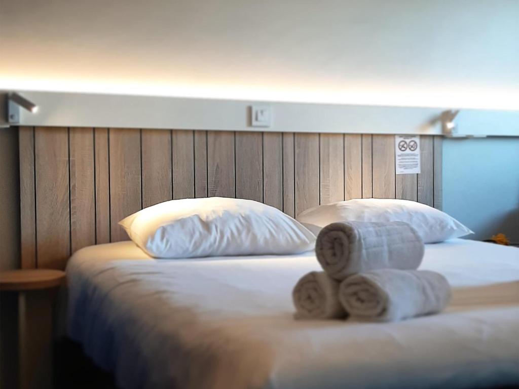 a bed with two rolled towels on top of it at ibis Rennes Cesson in Cesson-Sévigné